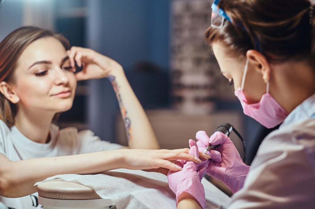 Process of manicure at beuaty with two attractive womens.